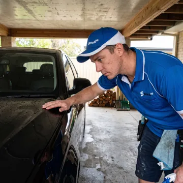 Detailer inspecting a polished car panel