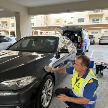 Technician cleaning and waxing a car at home