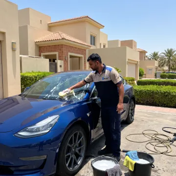 Mobile technician washing a car at a parking space