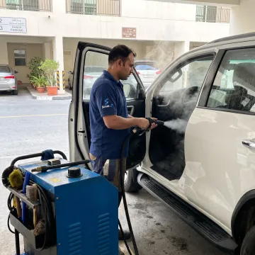 Technician cleaning a car at a Dubai parking space