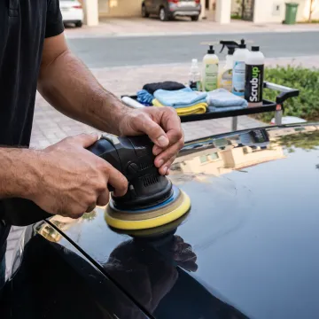 Car paint being polished by a detailing technician