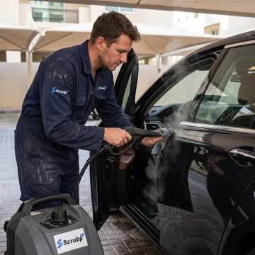Technician cleaning a car door panel in Dubai
