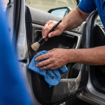 Detailer cleaning car door seals and storage pocket