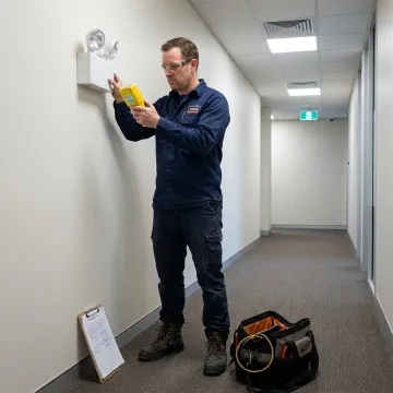 Electrician testing an emergency light fixture