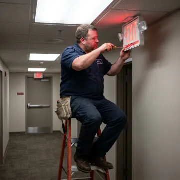 Technician repairing an illuminated emergency exit sign
