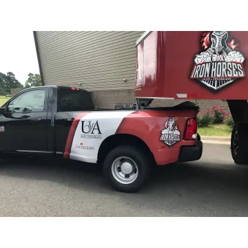 A commercial van with vibrant, custom vehicle graphics driving down a city street.