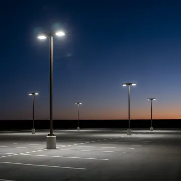 Brightly lit commercial parking lot at dusk after new LED light installation.