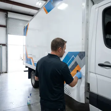 Technician installing a custom vinyl graphic on a truck.