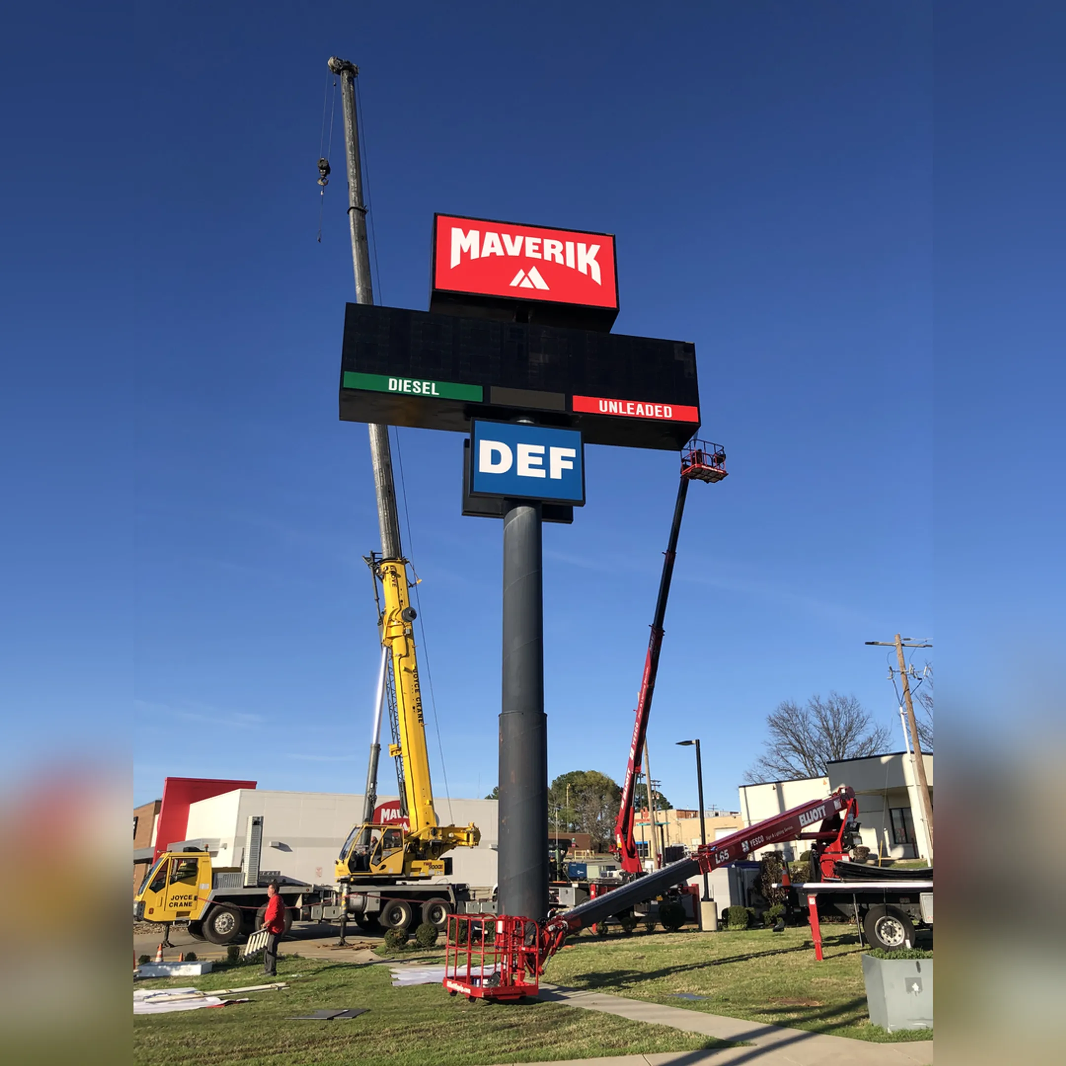 A team of technicians using a crane to install a large commercial pole sign.