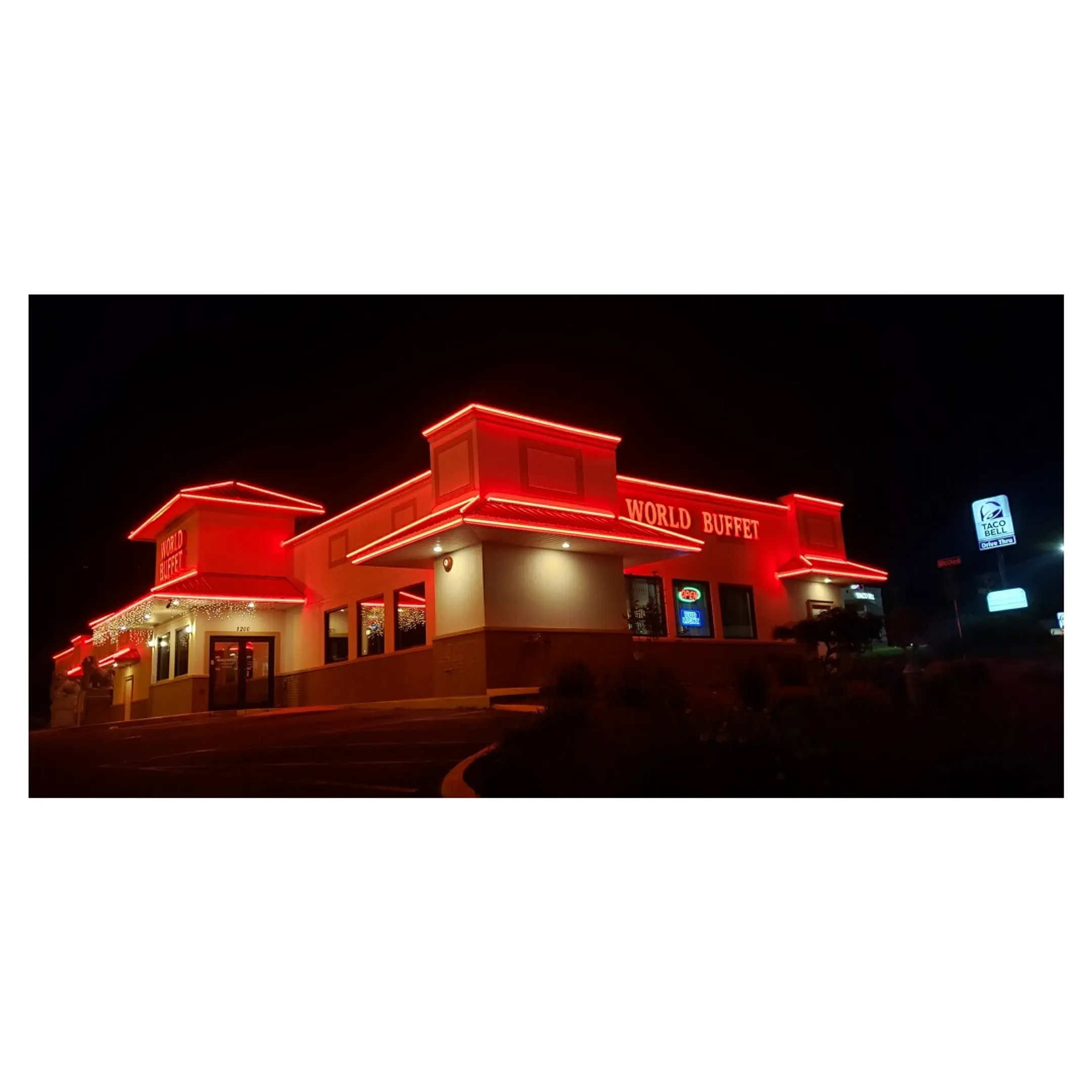 A brightly illuminated and fully restored commercial business sign at night.