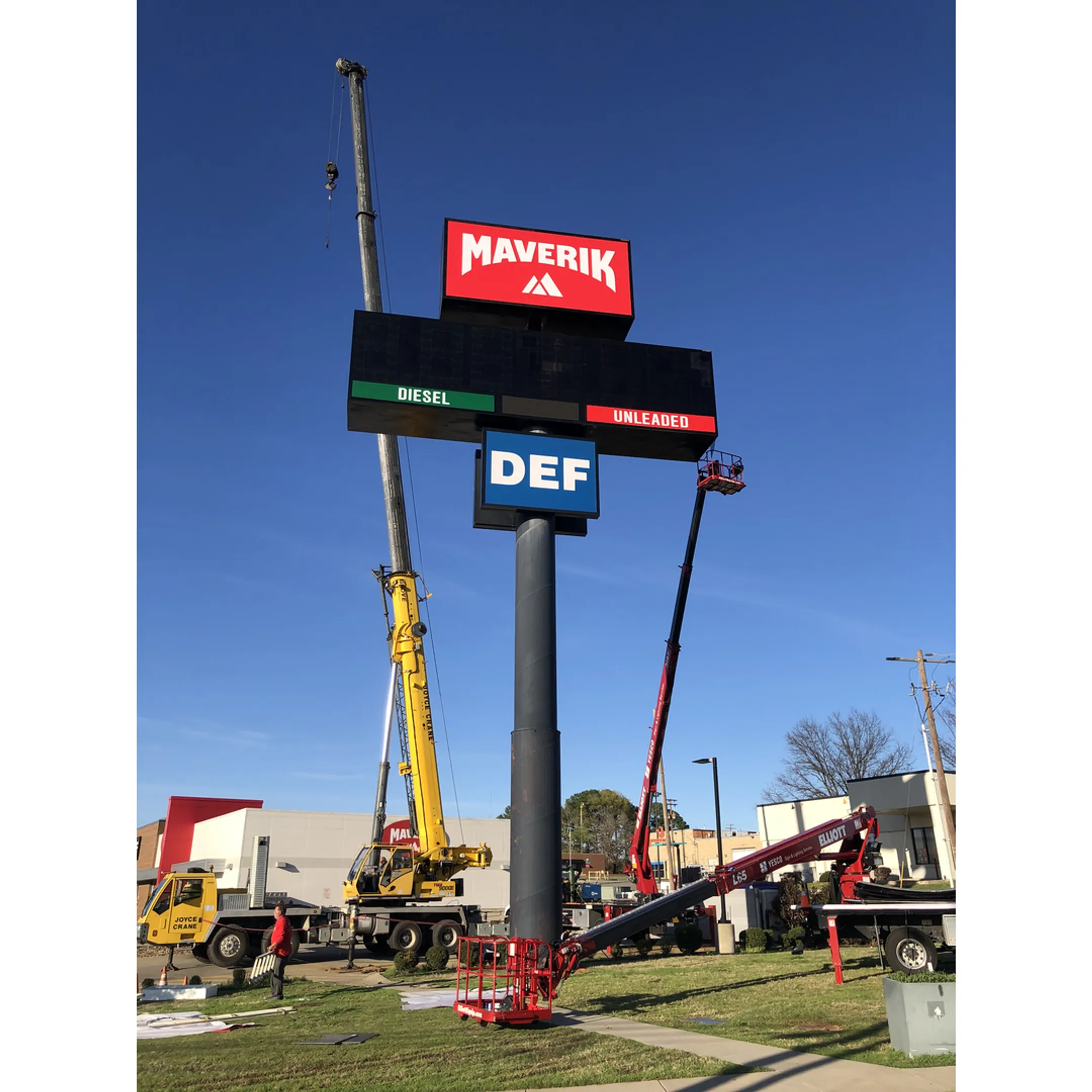 A team of technicians using a crane to install a large commercial pole sign.