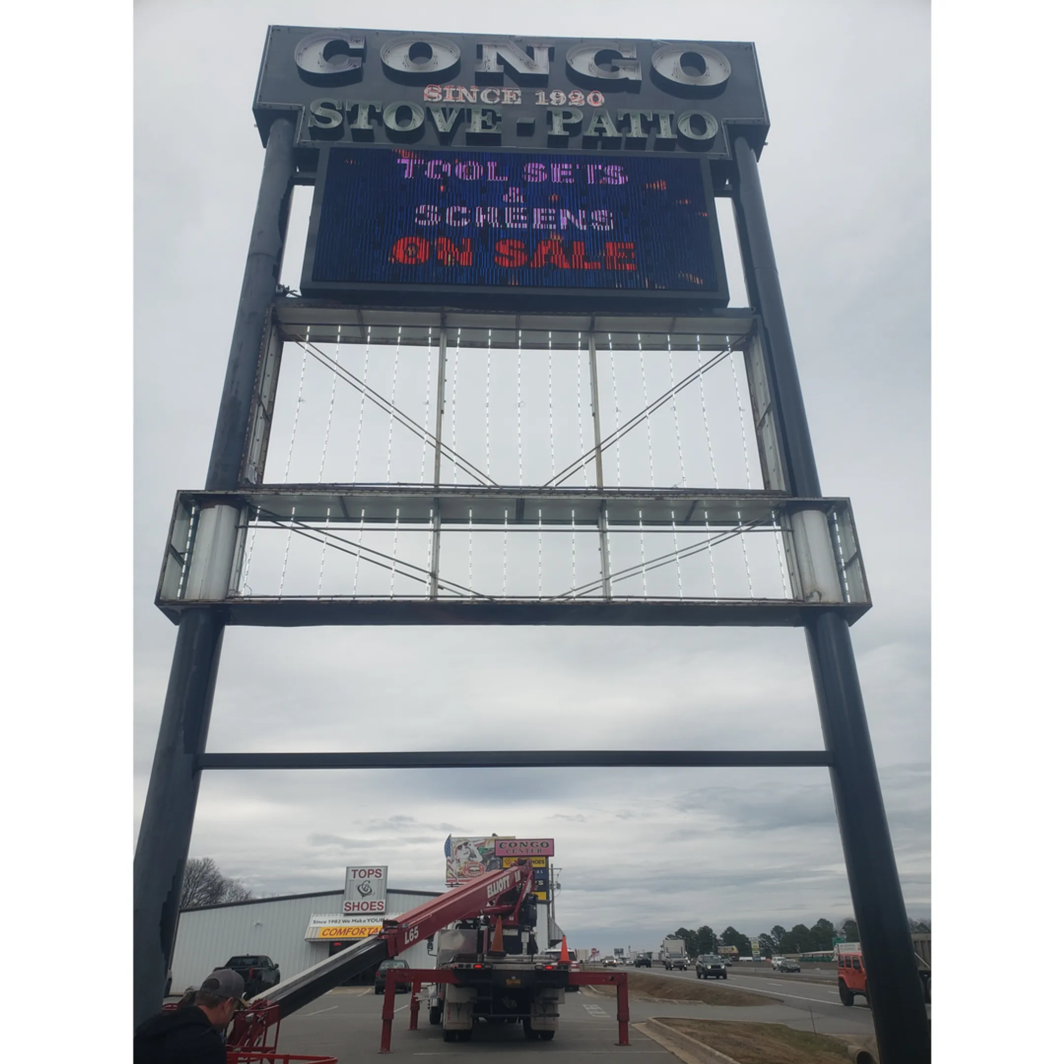 Technician in a bucket truck repairing an illuminated commercial sign.