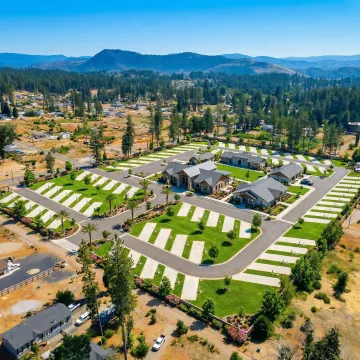 Aerial view of a well-maintained RV park with paved sites, utility hookups, and amenity buildings surrounded by green landscaping
