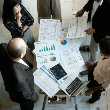 Professional tax planning team reviewing real estate investment documents with financial charts and property blueprints