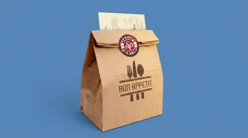 Branded restaurant takeout bag with logo sticker and packaging insert visible