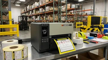 Industrial label printer producing GHS chemical labels and pipe markers on facility floor