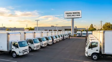 Busy truck rental lot during peak moving season with multiple pickup trucks available