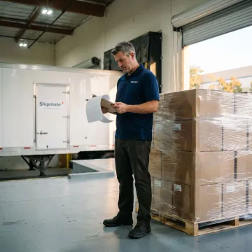 Freight specialist reviewing paperwork near palletized cargo