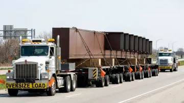 Heavy haul multi-axle lowboy trailer transporting large steel structural components on highway