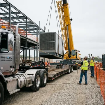 Crane lifting heavy machinery at a job site
