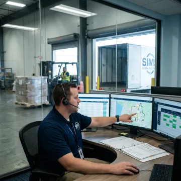 Freight coordinator tracking shipments on logistics screens