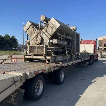 Open deck flatbed trailer carrying industrial machinery