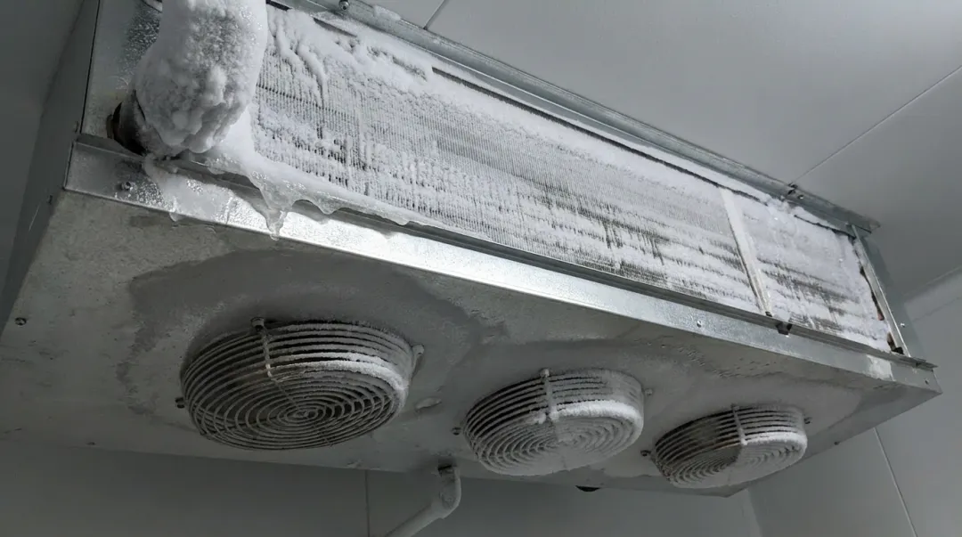 Frosted evaporator coil fins showing ice buildup inside walk-in cooler