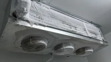 Frosted evaporator coil fins showing ice buildup inside walk-in cooler