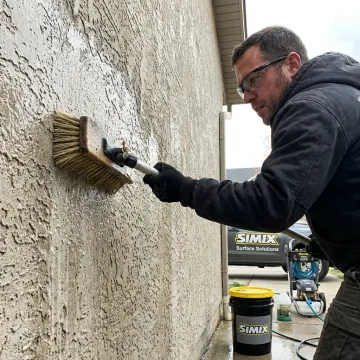 Technician cleaning stucco wall before coating