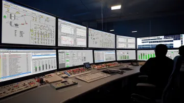Industrial control room with multiple PID-controlled process loops displayed on monitoring screens