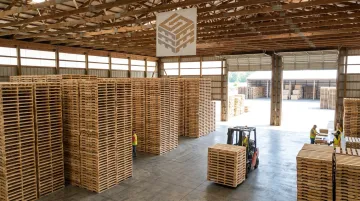 Kiln-dried wood pallets in block stringer and wing constructions stacked in warehouse