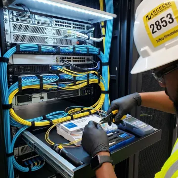 Technician installing structured fiber optic cabling in data center server rack