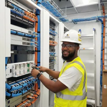 Network engineer configuring fiber optic WAN equipment in enterprise telecommunications room