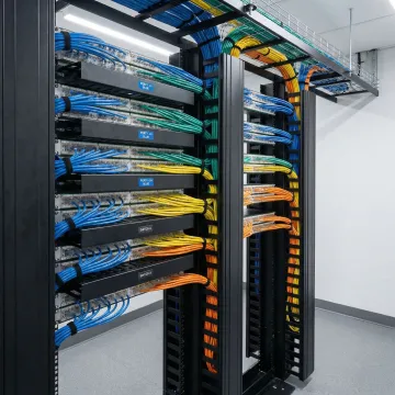 Professional technician organizing network cables in server rack with structured cable management system