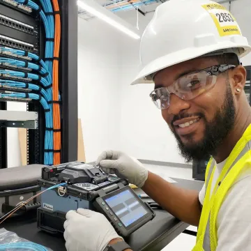 Technician performing fiber optic cable termination in modern data center