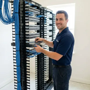 Certified technician installing network hardware in communication rack