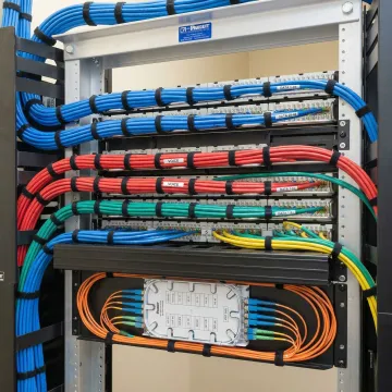 Organized network rack with labeled Cat6 cables and fiber optic connections in professional installation