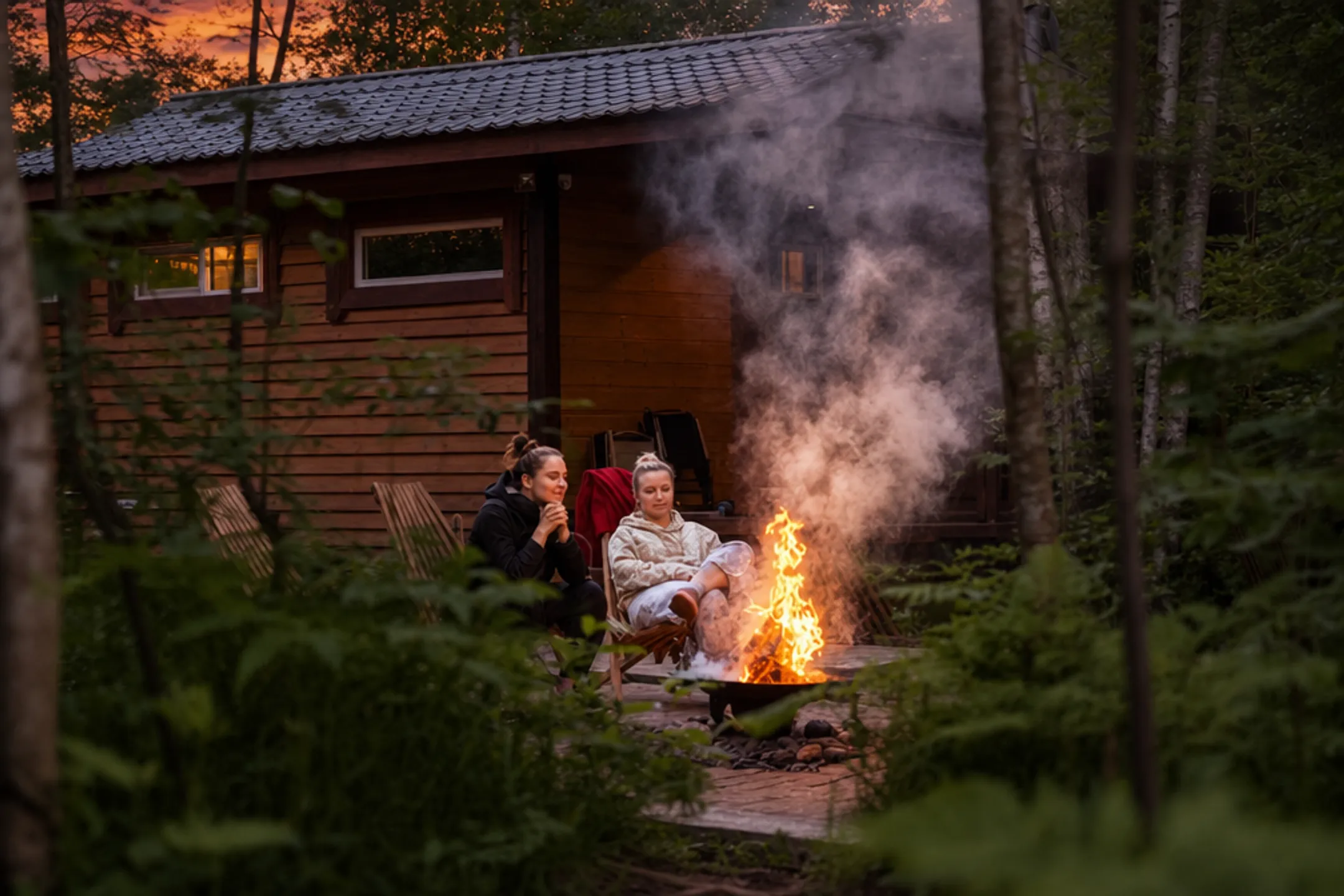 Campfire smoke rising at dusk near forested campsite deterring insects