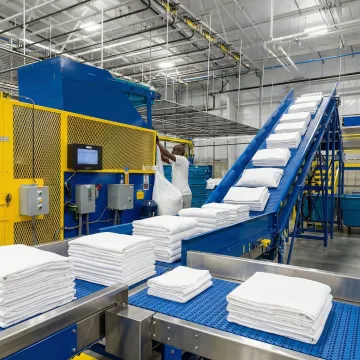 Modern hotel laundry facility with automated linen management system processing white towels and bedding