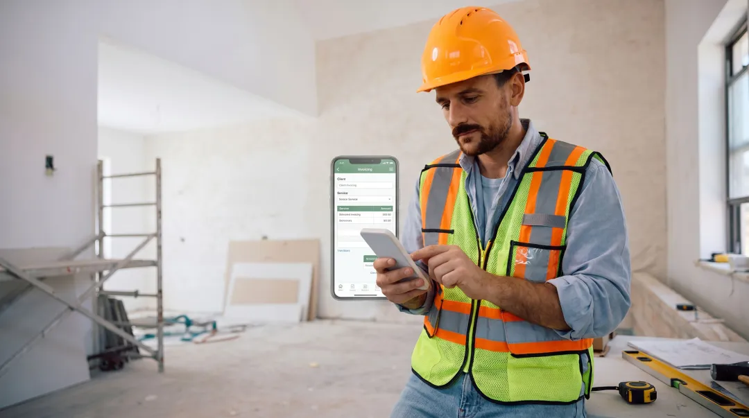 Plumber using a mobile job management app on a smartphone at a job site