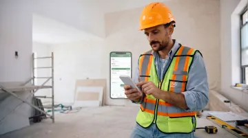 Contractor using mobile invoicing app on smartphone at job site
