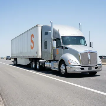 A modern semi-truck on a highway, representing physical damage insurance for trucking.