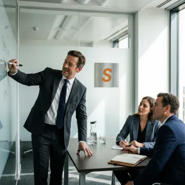 A management consultant confidently leading a business meeting in a modern office.