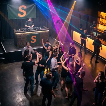A vibrant nightclub with people dancing under neon lights.