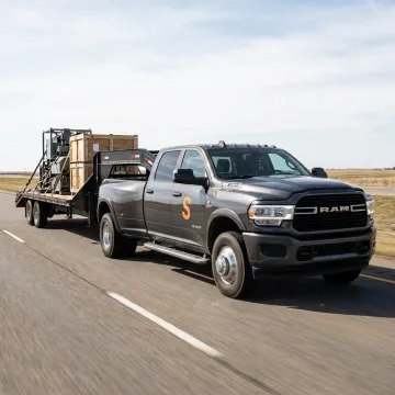 A hotshot truck with a gooseneck trailer securely hauling equipment on a highway.