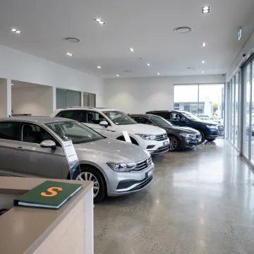 A well-lit car dealership showroom with several new cars on display.