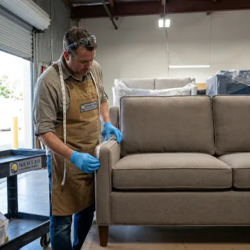 Upholstery professional inspecting a restored commercial sofa