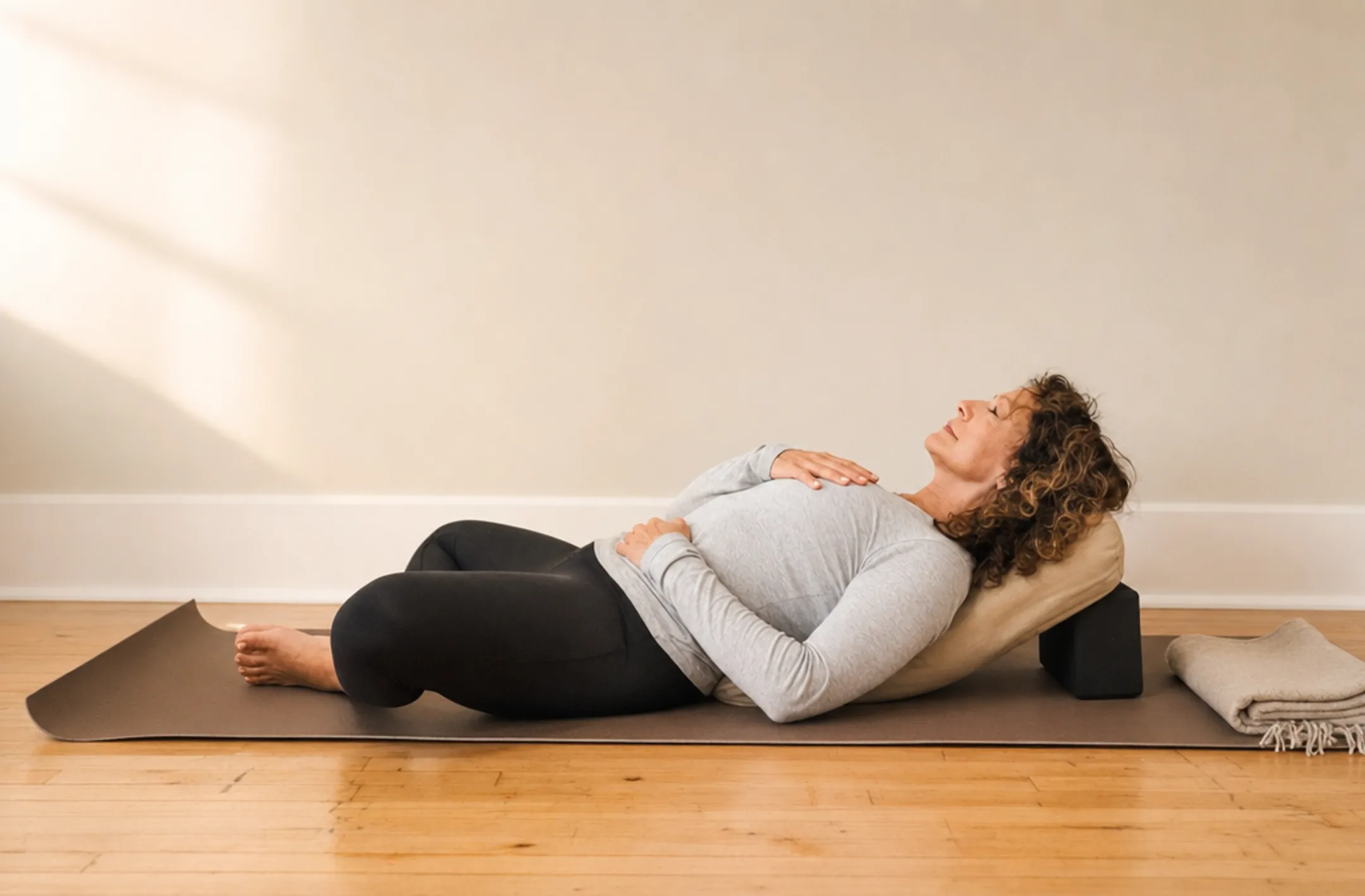 Person practicing restorative reclining bound angle yoga pose indoors