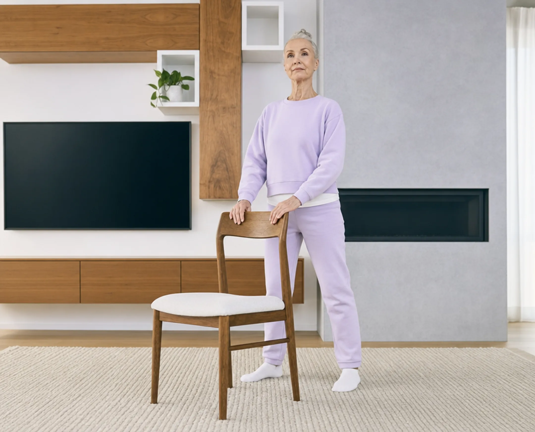 Senior woman practicing balance exercise with chair support in bright room