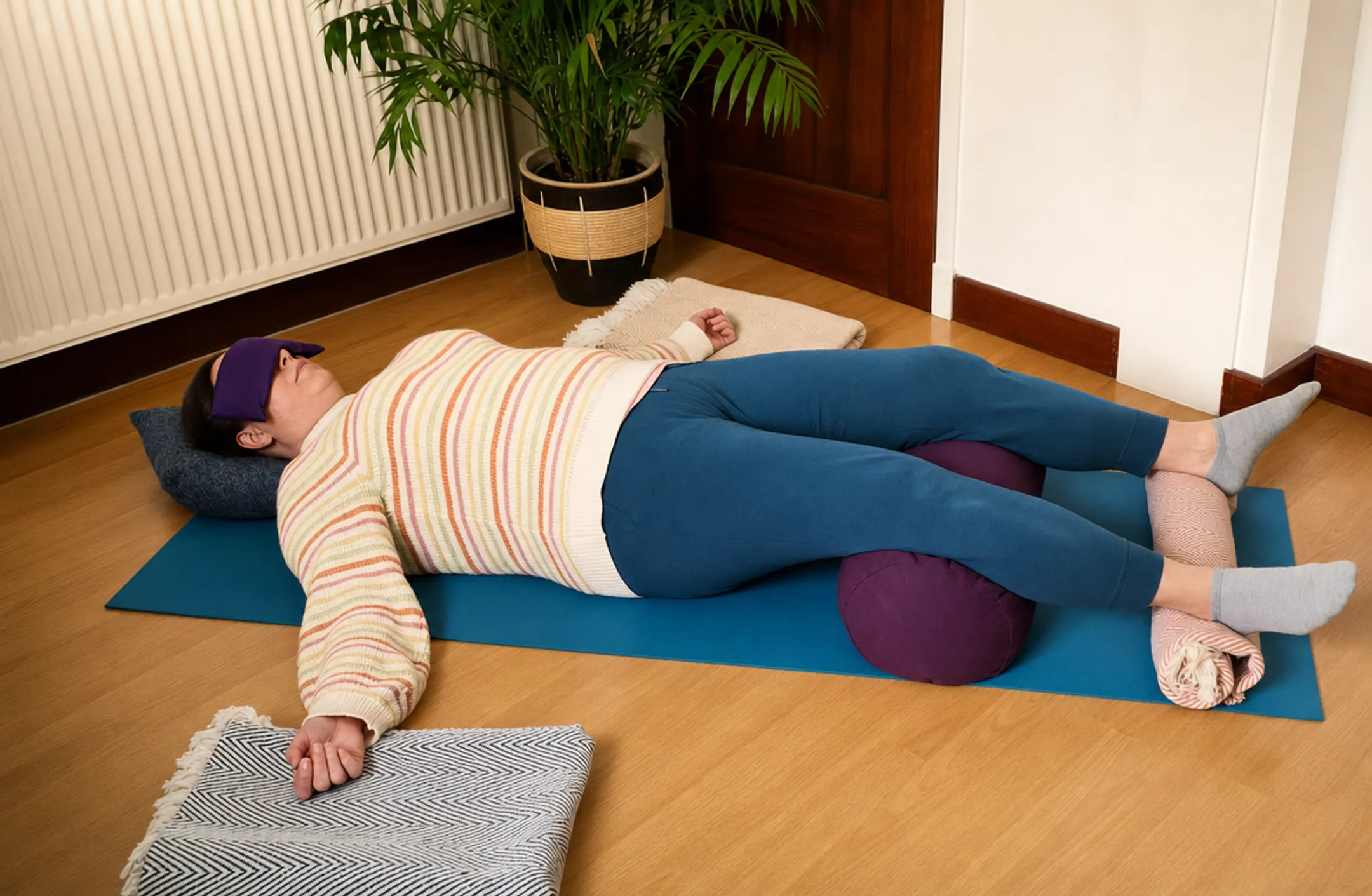 Person practicing gentle restorative yoga pose with props on mat